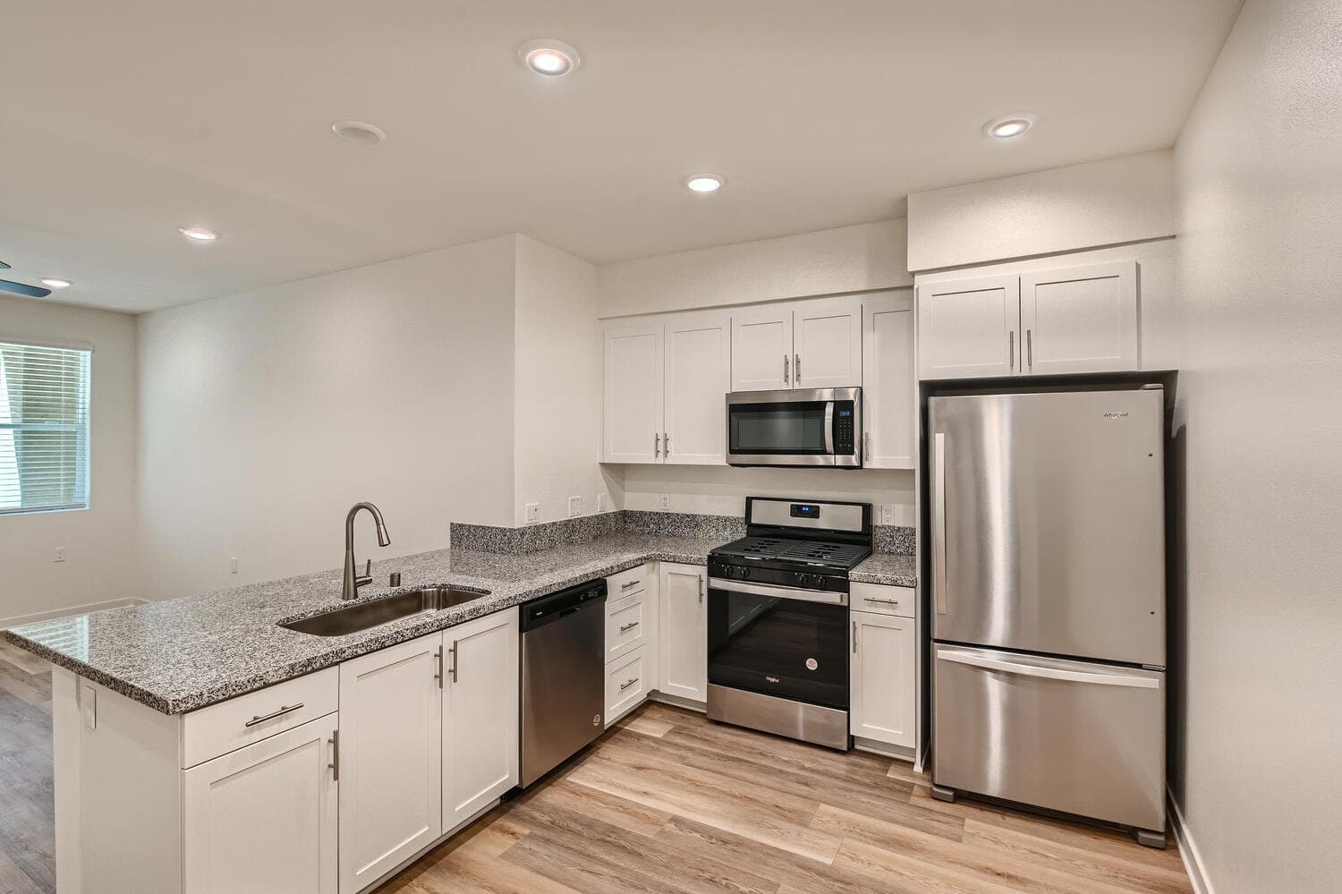 Open concept kitchen with granite countertops and white cabinetry